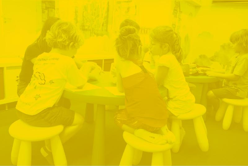 Niños pequeños sentados con su tutora participando en una sesión educativa.